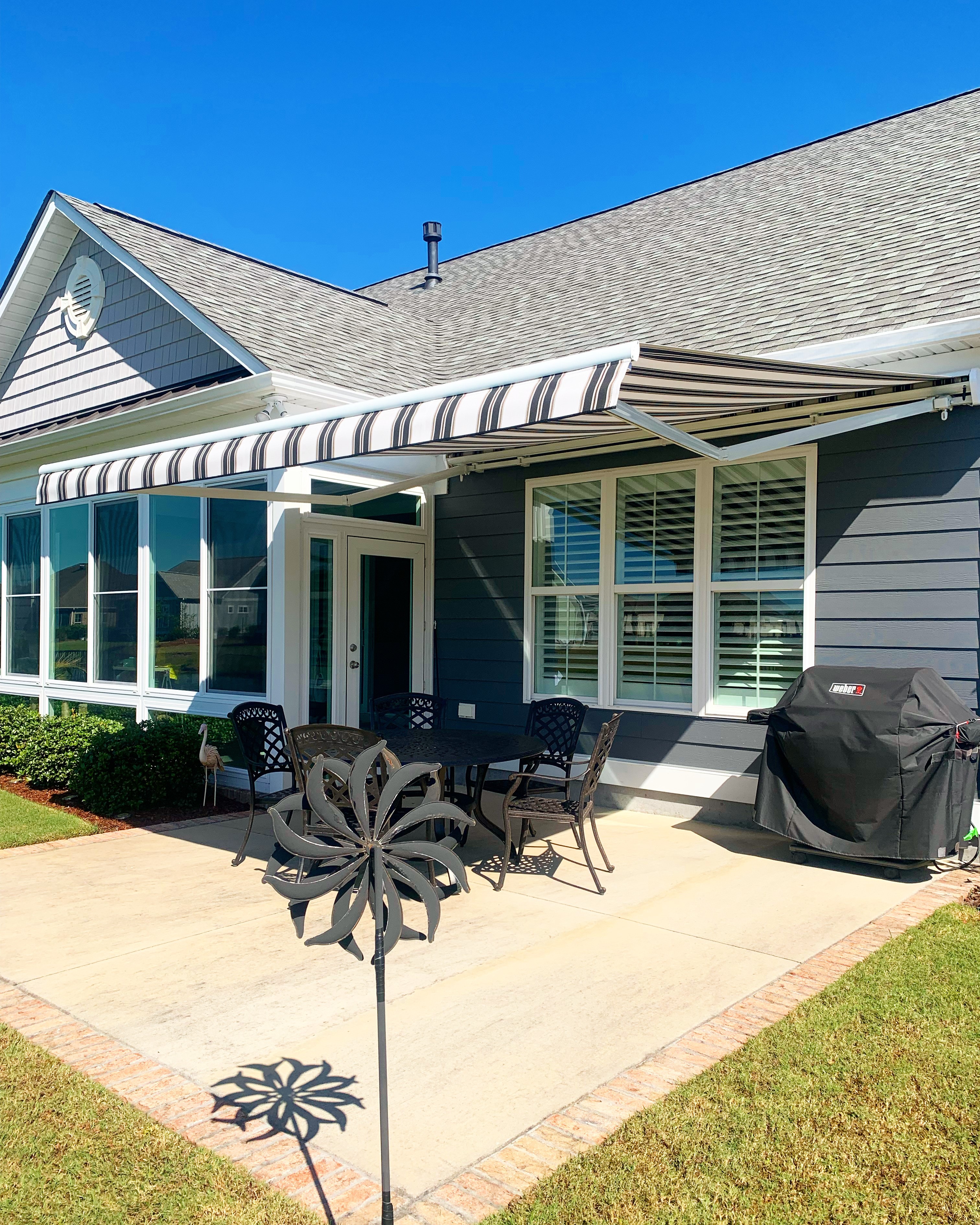 Striped retractable awning over a patio dining set